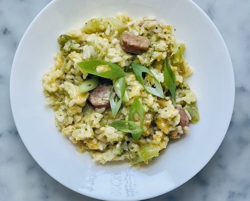 A white bowl of broccoli cheddar sausage risotto.