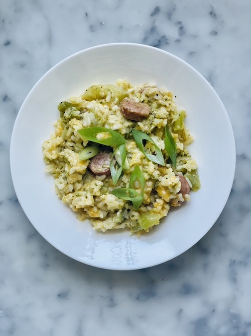 A white bowl of broccoli cheddar sausage risotto.