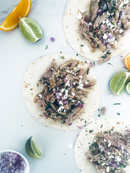 Chicken carnitas on flour tortillas on a white surface.