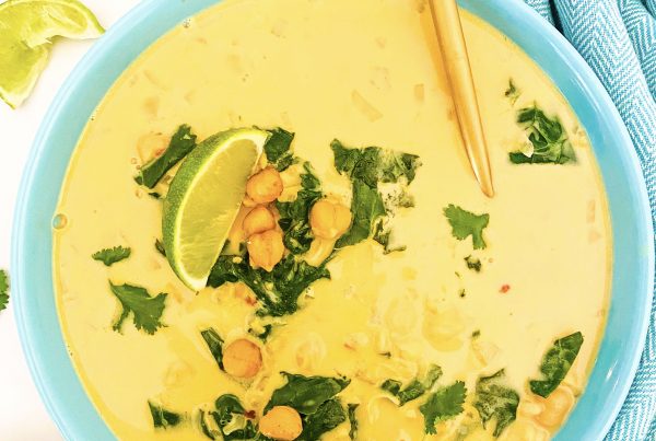 Creamy chickpea kale coconut soup in a blue bowl with a gold spoon.