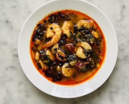 A white bowl of chorizo, shrimp, and white bean stew.