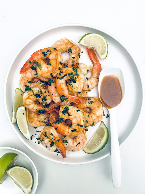 Citrus grilled shrimp and lime wedges on a white plate.