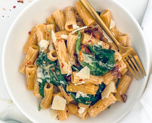Creamy Tuscan rigatoni pasta in a white bowl.