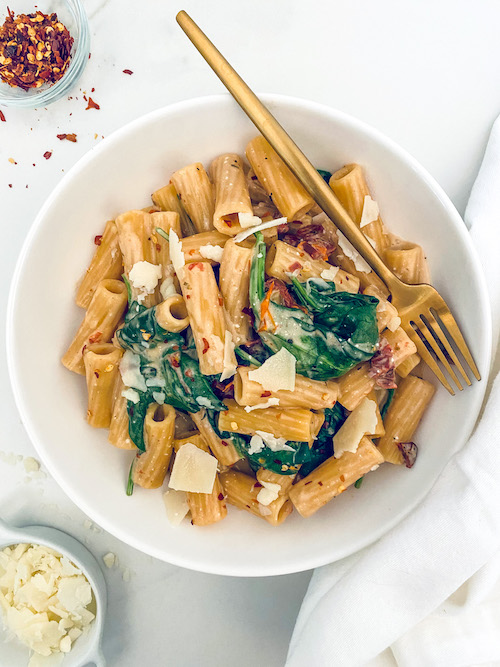 Creamy Tuscan rigatoni pasta in a white bowl.