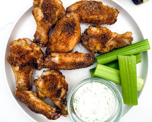 Crispy cumin chicken wings with celery on a plate.