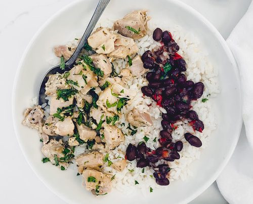 A white bowl of Cuba mojo chicken with white rice and red beans.