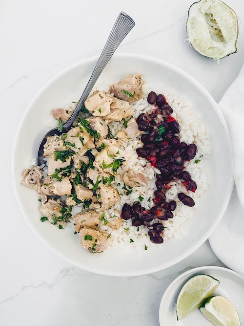 A white bowl of Cuba mojo chicken with white rice and red beans.