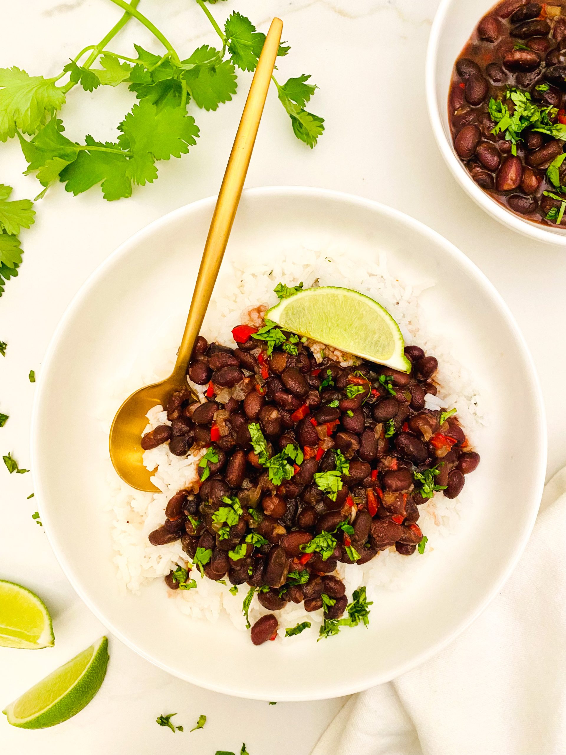Cuban black beans over rice with lime wedges in a white bowl.