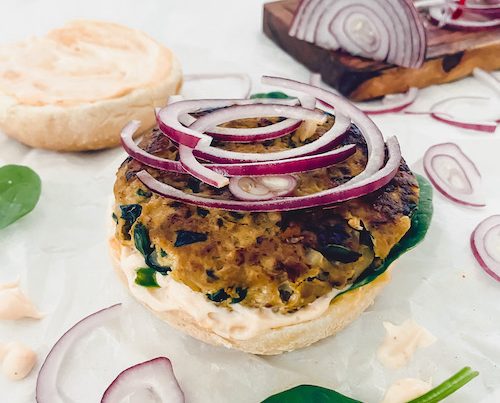 A juicy turkey burger on a bun topped with red onion slices.