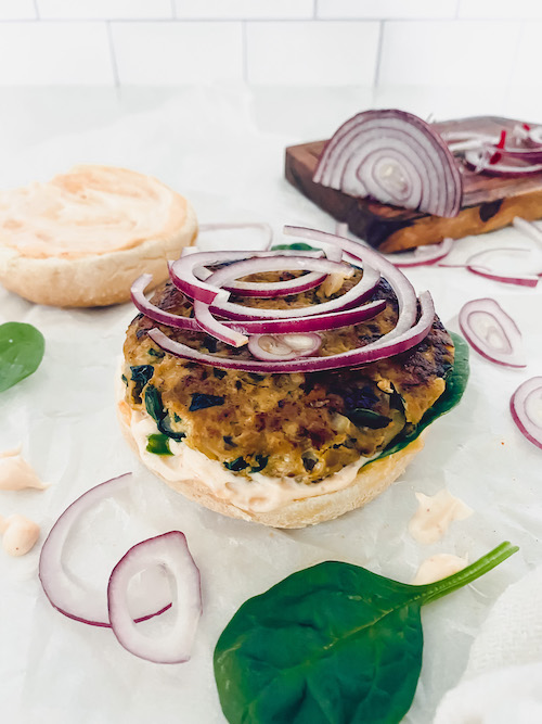 A juicy turkey burger on a bun topped with red onion slices.