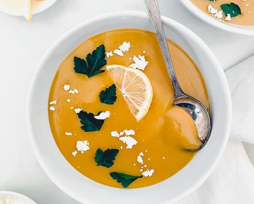 A white bowl of blended lemon red lentil soup.