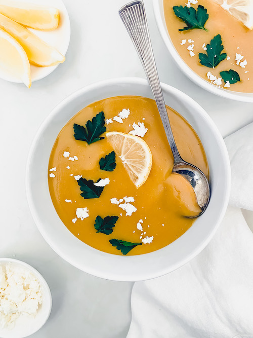 A white bowl of blended lemon red lentil soup.