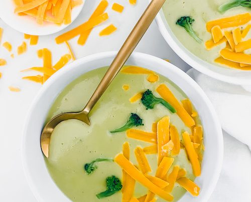 Two small white bowls of loaded broccoli cheddar potato soup.