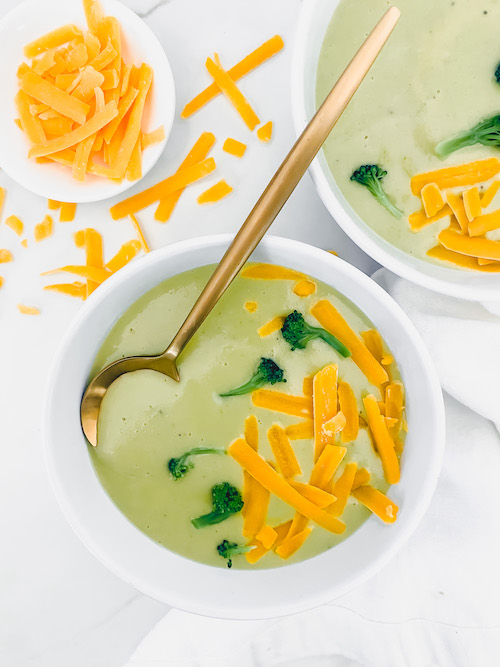 Two small white bowls of loaded broccoli cheddar potato soup.