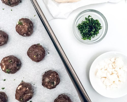Mediterranean meatballs on a parchment lined baking sheet.