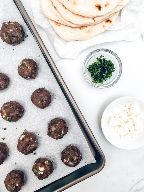 Mediterranean meatballs on a parchment lined baking sheet.