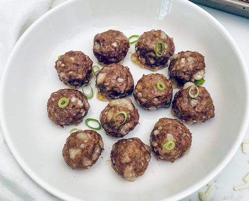 Philly cheesesteak meatballs in a white pasta bowl.