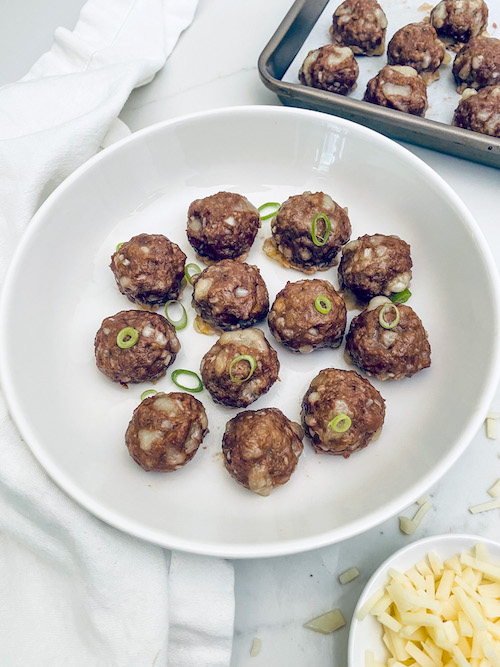 Philly cheesesteak meatballs in a white pasta bowl.