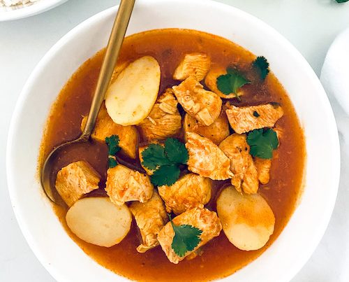 Pollo Guisado and a spoon in a white bowl.