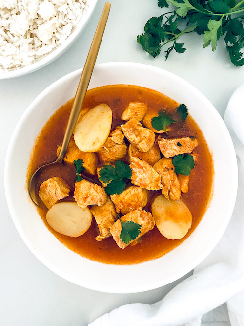 Pollo Guisado and a spoon in a white bowl.