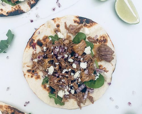 A pork al pastor taco on a white counter.