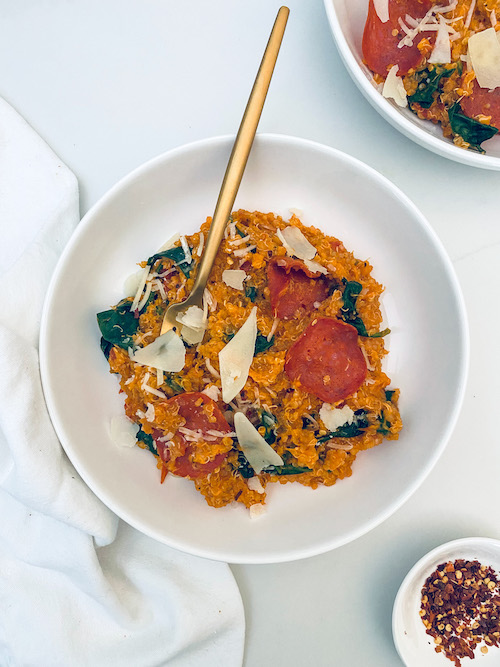 Pizza flavored quinoa with a gold fork in a white bowl.