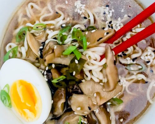 A vegetarian Ramen noodle bowl with red chopsticks.