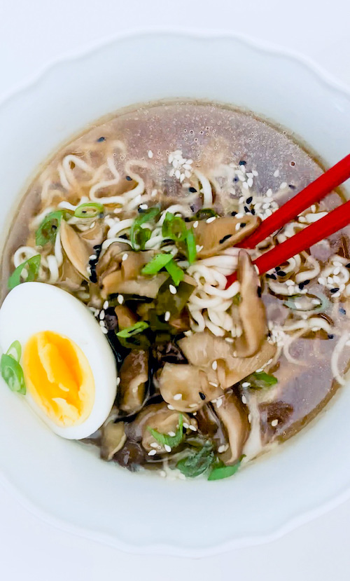 A vegetarian Ramen noodle bowl with red chopsticks.