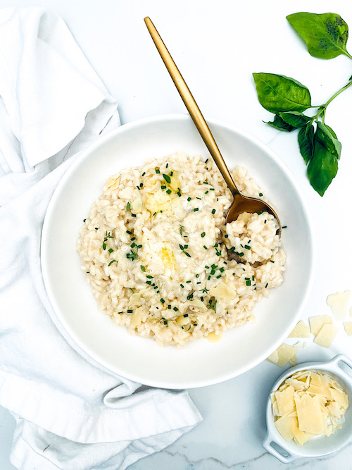 A white bowl with golden spoon filled with vegetarian risotto.