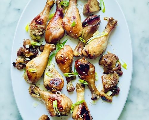 Honey soy drumsticks with roasted cauliflower on a white serving platter.