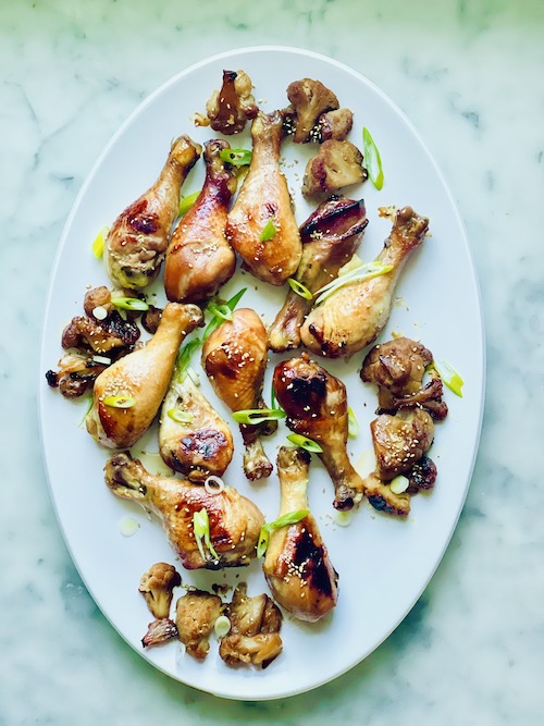 Honey soy drumsticks with roasted cauliflower on a white serving platter.