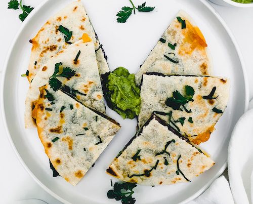 6 triangles of spinach and black bean quesadilla on a white plate.