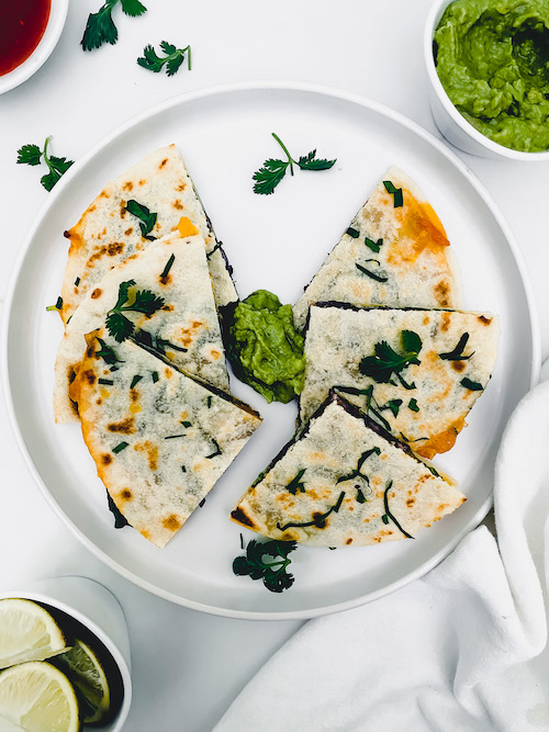 6 triangles of spinach and black bean quesadilla on a white plate.