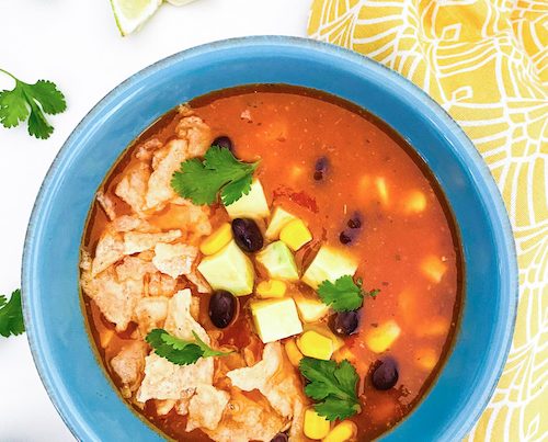 A blue bowl filled with vegetarian tortilla soup.