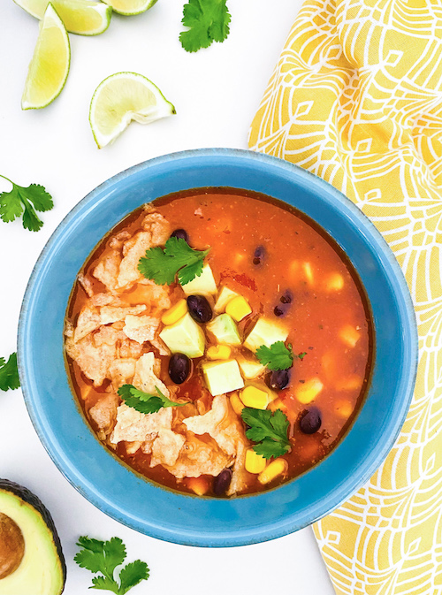 A blue bowl filled with vegetarian tortilla soup.