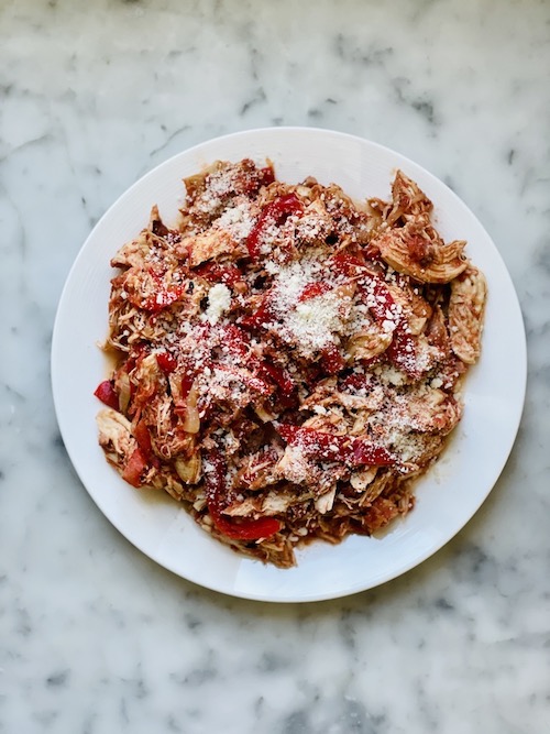 A white plate filled with chicken cacciatore.