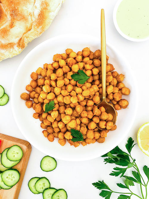 A white bowl of chickpea shawarma topped with parsley.