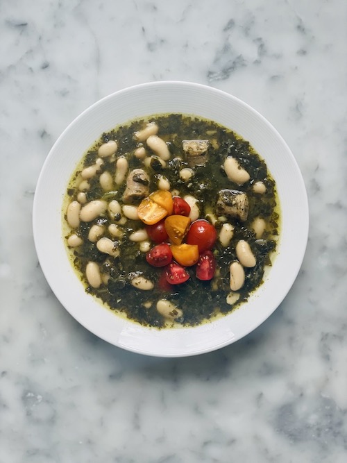 White bean and pesto soup in a white bowl.