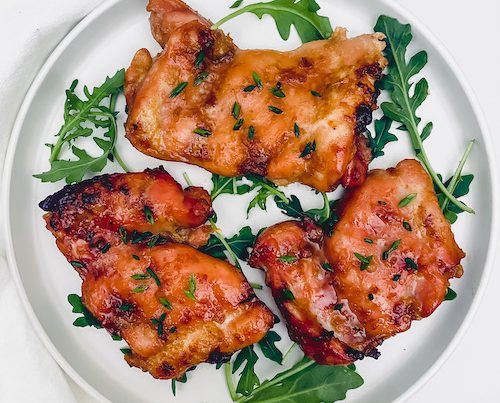 Brown Sugar Chicken on a plate with fresh arugula leaves.