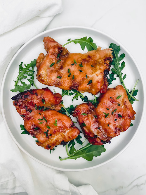Brown Sugar Chicken on a plate with fresh arugula leaves.