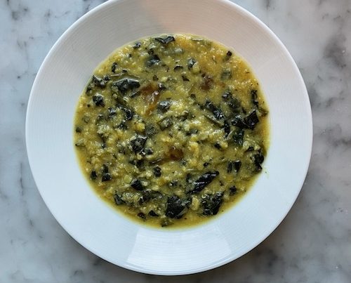 Curried lentil soup with spinach in a white bowl.