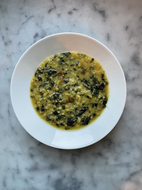 Curried lentil soup with spinach in a white bowl.
