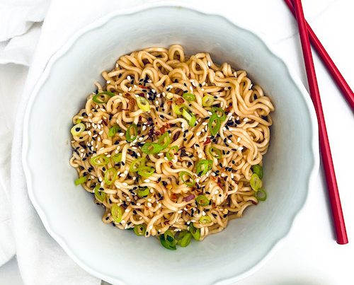 Garlic Chili Ramen Noodles in a bowl on the counter with a set of red chopsticks.