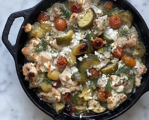 Greek chicken with zucchini in a cast iron skillet.