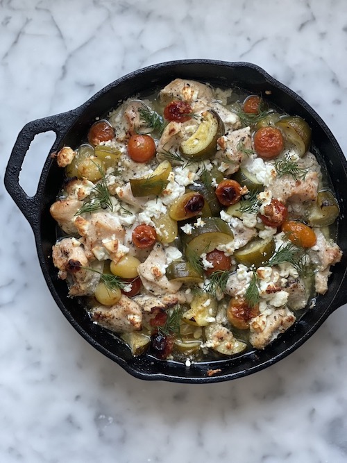 Greek chicken with zucchini in a cast iron skillet.