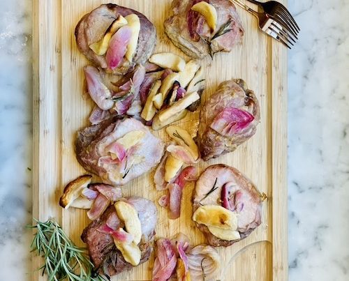Honey-Mustard Pork Chop, Apple and Onion Sheet Pan Dinner on a wooden cutting board.