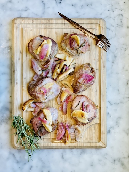 Honey-Mustard Pork Chop, Apple and Onion Sheet Pan Dinner on a wooden cutting board.