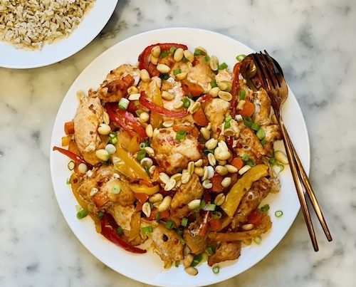 Kung Pao Chicken Sheet Pan on a plate next to a bowl of brown rice.