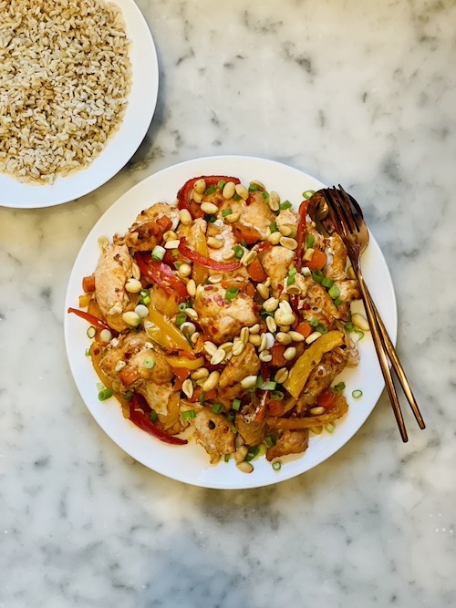 Kung Pao Chicken Sheet Pan on a plate next to a bowl of brown rice.