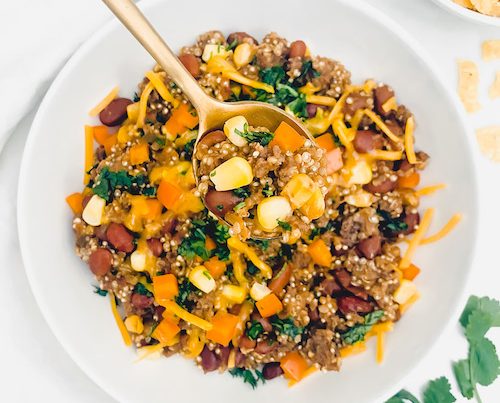 Mexican Casserole in a large white bowl with a golden spoon.